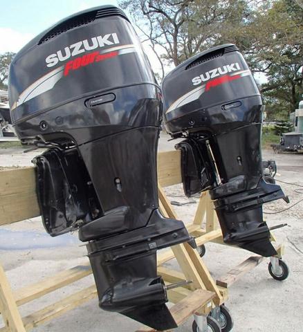 Two Suzuki outboard motors mounted on a display stand showcasing their sleek black design and branding