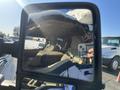 A cracked side mirror reflecting the interior of a 2014 Ford F-350 SD with a person holding a smartphone visible in the mirror