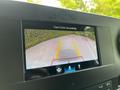 Display screen showing a rearview camera view of a Mercedes-Benz Sprinter with yellow guiding lines on a road