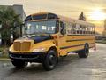 A 2013 International 4300 school bus with a bright yellow exterior and black accents parked on a driveway