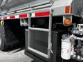 A 2010 Freightliner M2 106 featuring a metal ladder attached to the back with a black battery box and various mechanical components visible