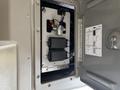 A metal panel with two mounted black devices and various wires connected to them inside a Chevrolet Express vehicle