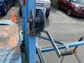 A close-up of the winch mechanism on a 2003 U-Built Reel Trailer featuring a circular spool with wire and a lever attached for operation