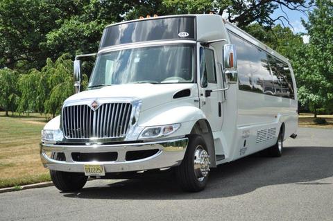 A white limo bus with shiny chrome details parked on a street showcasing its spacious design and sleek appearance ideal for group transportation in Philadelphia