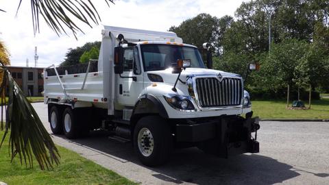 A 2014 International 7500 truck with a white dump bed, large chrome grille, and side mirrors parked on the road