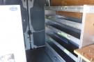 Interior of a 2012 Mercedes-Benz Sprinter van featuring metal shelving units along one side and a rear opening for access