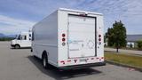 A white 2011 Ford Econoline van with a plain rear door and signage indicating it is a hybrid-electric vehicle