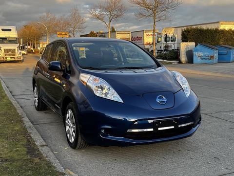 A blue 2016 Nissan LEAF parked on a street with a modern design featuring a smooth front grille and distinctive headlights
