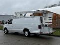 White 2009 Ford Econoline van with a raised bucket lift attached to the roof and a toolbox mounted on the rear bumper