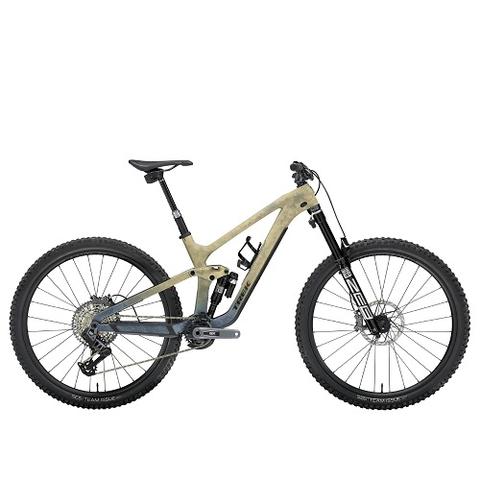 A 2025 Trek Slash SE Gen 5 Mountain Bike featuring a beige frame prominent suspension fork and wide tires designed for rugged terrain