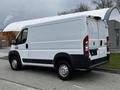 A white 2018 RAM Promaster van viewed from the rear showing its sliding side door and rear doors with no visible markings or logos