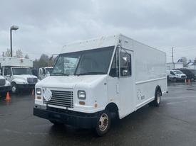 A white 2012 Ford Econoline delivery truck with a boxy shape and large front windows parked in a lot