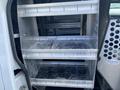 A 2013 Ford Transit Connect with metal shelving units inside the cargo area designed for storage and organization