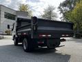 A 2015 Mitsubishi Fuso FE flatbed truck with a black cargo bed and red and white reflective markings on the sides
