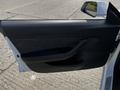 A 2019 Tesla Model 3 car door with a sleek interior design featuring fabric and leather materials and a minimalist handle