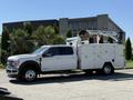 A 2024 Ford F-550 Super Duty truck with a white exterior and a utility box mounted on the back featuring a raised work platform and equipment storage compartments