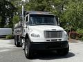 A white 2010 Freightliner M2 106 dump truck with a silver cargo bed and dual rear axles is parked in a lot