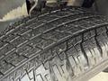 Close-up view of a 2021 Toyota 4Runner tire showing deep tread patterns and some dirt particles embedded in the rubber
