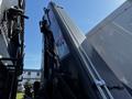 Side view of a 2012 Freightliner M2 112 with a hydraulic arm extended upward against a clear blue sky
