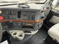 Interior dashboard of a 2012 Volvo VNL with buttons knobs a radio and cup holders in a gray and black color scheme