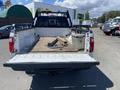 A white 2016 Ford F-350 SD truck with an open bed containing a wooden plank and a toolbox inside the cargo area