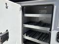 A 2016 Ford F-550 utility truck with an open storage compartment featuring metal shelves and various tools arranged inside