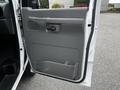 A gray interior door of a 2008 Ford Econoline van with a handle and storage compartment visible