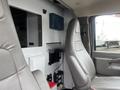 Interior view of a 2016 Chevrolet Express showing a driver's seat and dashboard area with storage compartments and a clean design