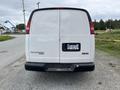 A white 2014 GMC Savana van viewed from the rear featuring a clean design with the model name and brand logo visible on the back door