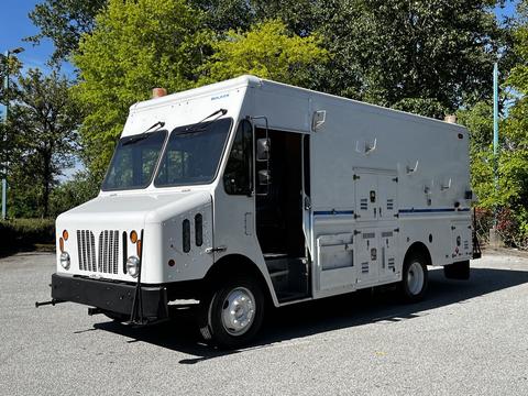 A 2009 Morgan Olson Workhorse delivery truck with a white exterior multiple storage compartments and an open side door