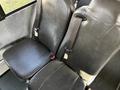 Two black leather seats with seat belts in a vehicle, positioned next to each other