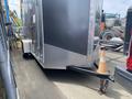A 2020 Stealth Enterprises trailer with a silver exterior and diamond plate accents attached to a vehicle by a hitch and a traffic cone positioned at the coupler