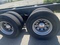 Close-up view of two large tires mounted on a wheel with a silver rim on a truck chassis