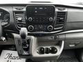Interior of a 2023 Ford Transit featuring a central dashboard with various controls a gear shift and cup holders