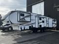 A 2021 Grand Design Reflection 311BHS recreational vehicle with a sleek white exterior and multiple slide-outs is parked with its doors open