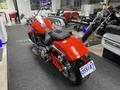 A 2024 Harley Davidson Fat Boy motorcycle in bright red with chrome accents and a low, streamlined design viewed from the rear