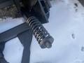 A heavy-duty metal spring attached to a black structure designed for a plow attachment