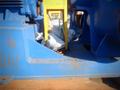 A blue industrial machine with a yellow support structure and part of a protective tarp partially covering it