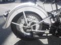 A vintage 1947 Harley-Davidson WL motorcycle featuring a chrome rear fender and spokes on the rear wheel with a chain drive and exhaust visible