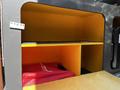 A cargo space in a 2017 Mercedes-Benz Sprinter features a yellow interior with a red bag placed on the bottom shelf