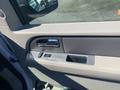Interior view of a 2013 Ford Expedition door panel featuring a silver door handle power window control and a storage compartment