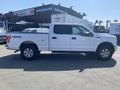 A white 2017 Ford F-150 with four-wheel drive and a covered truck bed parked with a side view visible