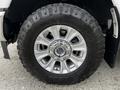 A close-up of a silver wheel from a 2020 Ford F-350 featuring a rugged tire with deep treads and a chrome hubcap displaying the brand name
