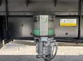 A Groenveld single line lubricator attached to the underside of a truck with a clear housing and visible oil reservoir