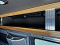 A 2017 Mercedes-Benz Sprinter interior featuring a wooden shelf with a metallic panel underneath and fabric storage pockets attached to the side