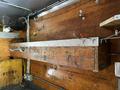 A wooden box with metal fittings mounted on a wall, featuring hooks and a metal strip along the top, part of the interior of a vehicle or work area