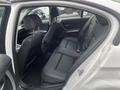 Interior view of a 2011 BMW 3-Series showing the back seat with black leather upholstery and two headrests