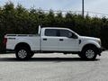 A white 2017 Ford F-250 SD with a crew cab and four-wheel drive features a flatbed and chrome wheels