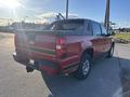 A red 2011 Chevrolet Avalanche with a black bed cover and chrome rims is parked with its rear angled towards the viewer