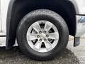 A close-up view of a silver alloy wheel of a 2015 GMC Sierra 1500 featuring a black tire with the Scorpion AT2 label on the sidewall